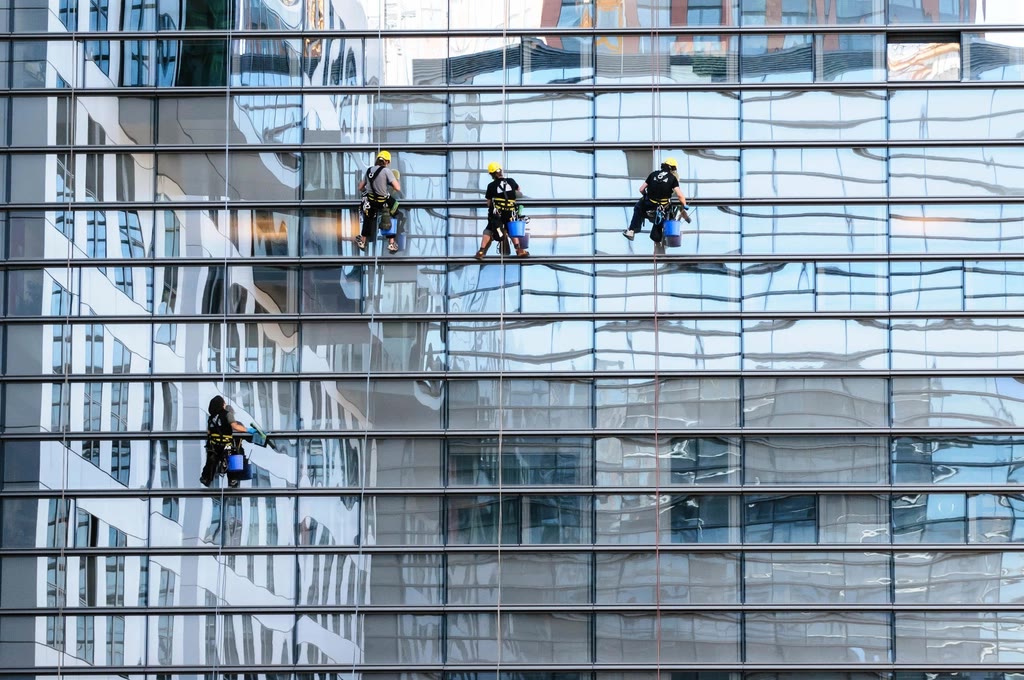 Professional cleaners cleaning the glass facade of a commercial building